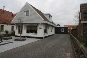 a white house with a brick driveway at Bed & Breakfast Aalsmeer in Aalsmeer