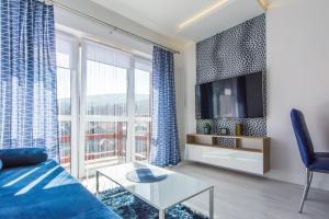 a living room with a blue couch and a large window at Apartamenty Izerskie - ul. Sienkiewicza 9 in Świeradów-Zdrój