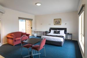a hotel room with a bed and a table and chairs at Best Western Mill Park Motor Inn in Morang