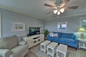 a living room with a blue couch and a tv at Bright Emerald Isle Condo with Private Beach Access! in Emerald Isle