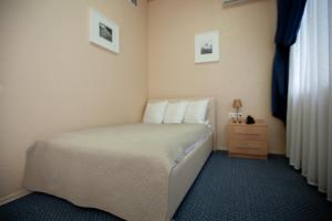 a bedroom with a bed with white pillows and a dresser at Hotel Yubileinaya in Syzran'