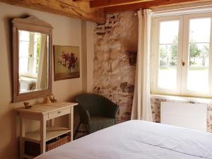 a bedroom with a bed and a chair and a window at La ferme aux grenouilles in Saint-Josse