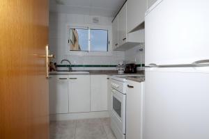 a white kitchen with white cabinets and a window at Apartamentos Sunway Tara in Sitges