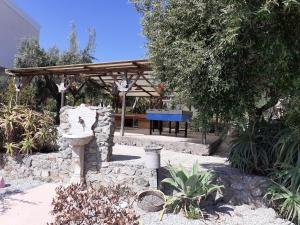 a garden with a stone fountain and a wooden pergola at agriturismo heaven in Capo Vaticano