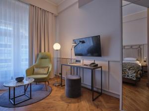 a hotel room with a desk and a chair and a television at Classik Hotel Alexander Plaza in Berlin