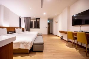 Cette chambre comprend un grand lit et un bureau. dans l'établissement Beauty Avenue Inn, à Kaohsiung