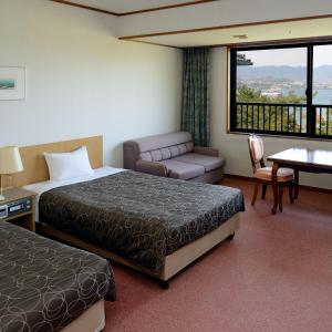 a hotel room with two beds and a couch and a table at Miyajima Morinoyado in Miyajima