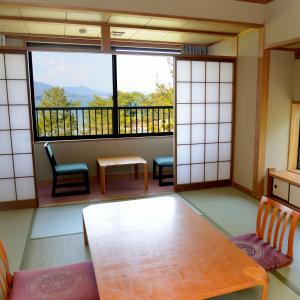 una stanza con tavolo e sedie e una grande finestra di Miyajima Morinoyado a Miyajima