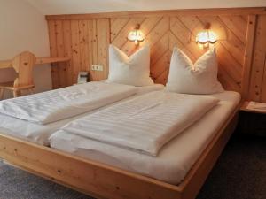 een groot bed met witte lakens en kussens bij Schieplechnerhof in Schladming