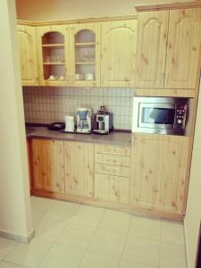 a kitchen with wooden cabinets and a microwave at Főnix Apartmanház in Nagypáli