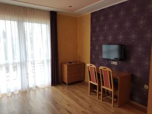 a room with a table and two chairs and a television at Főnix Apartmanház in Nagypáli