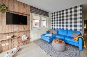 a living room with a blue couch and a tv at Haus Pamir _ Fewo 25 in Cuxhaven