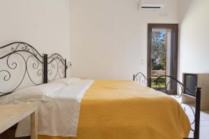 biała sypialnia z łóżkiem z żółtym kocem w obiekcie Agriturismo Podere San Giorgio w mieście Otranto