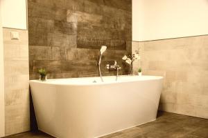 a white bath tub in a bathroom with a tile wall at SALUS Spreewald - Erholung & Natur - in Kolonie