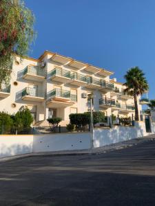 a large white building with palm trees and a street at Holiday Apartment Near The Sea in Galé
