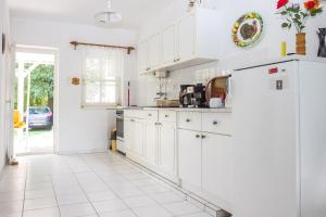バラトンマーリアフュルドゥーにあるFamilia Nyaraló 47の白いタイルフロアのキッチン(白いキャビネット付)