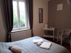 1 dormitorio con 1 cama con toallas y ventana en La Nouvelle Diligence, en Montsauche-les-Settons