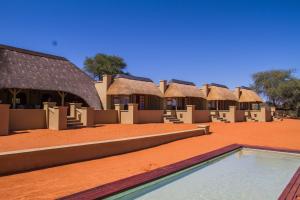 a row of huts in the desert with a swimming pool at Zebra Kalahari Lodge in Hoachanas