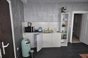 una pequeña cocina con armarios blancos y un cubo de basura en Ferienwohnung Kuckucksnest, en Helmstedt
