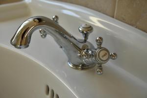 a bathroom sink with a silver faucet with a clock at Le Chant du coucou in Huy