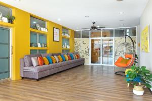 a living room with a couch and a yellow wall at Fullroom 77 Srinakarin in Samutprakarn
