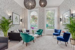 ein Wohnzimmer mit Sofa, Stühlen und Fenstern in der Unterkunft Mentone Hotel in London