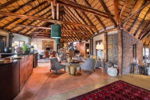 a large room with wooden ceilings with chairs and tables at Hoodia Desert Lodge in Sesriem