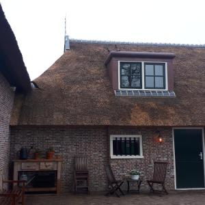 um edifício com um telhado com uma janela e cadeiras em B&B De Herenboer em Opeinde