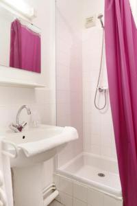 ein weißes Bad mit einem rosa Duschvorhang und einem Waschbecken in der Unterkunft Neoresid - Résidence Saint Germain in Amiens