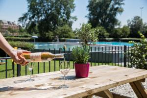 a person pouring wine into two glasses on a wooden table at WestCord Art Hotel Amsterdam 3 stars in Amsterdam