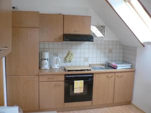 a small kitchen with wooden cabinets and a sink at Ferienwohnung Teubner in Bockau