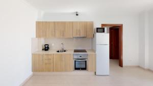eine Küche mit Holzschränken und einem weißen Kühlschrank in der Unterkunft Blancazul La Rociega in Playa Blanca