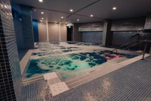 bañera de hidromasaje en un edificio con suelo cubierto de nieve en Hotel Aventus en Baile Felix