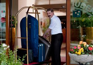 Un uomo è in piedi accanto a un portabagagli di Hotel Huber Hochland a Maurach