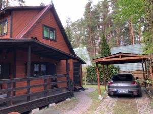 a house with a car parked in front of it at Domek nad jeziorem Głębokie in Głębokie