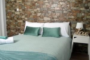uma cama com almofadas verdes e uma parede de tijolos em Cosy House em Albufeira