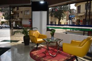 two yellow chairs and a table in front of a window at Hotel Briston in Cochabamba