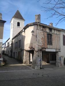 an old stone building with a tower on a street at Gîte La Bastide in Tournon-dʼAgenais