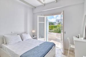Dormitorio blanco con cama y puerta corredera de cristal en Villa Mare, en Ampelas