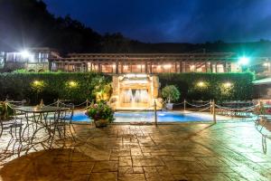 un patio nocturno con mesas, sillas y una fuente en B & B Le Casette sull'albero di Villa Alba, en Messina