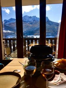 una mesa con copas de vino y vistas a las montañas en Appartement de vacances en Barcelonnette