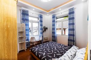 ダラットにあるKarry's Houseのベッドルーム1室(ベッド1台付)、青いカーテン付きの窓2つが備わります。