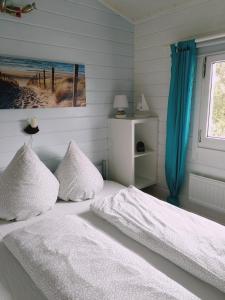 una camera da letto con un letto con lenzuola bianche e una finestra di Ferienhaus " Silly " am schönen Listersee a Meinerzhagen