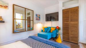 a bedroom with a blue couch and a mirror at Lemon Cottage - At Orange Hill in Nassau