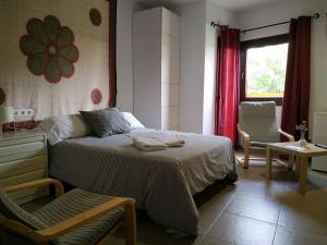 ein Schlafzimmer mit einem Bett, einem Stuhl und einem Fenster in der Unterkunft Centro de Naturaleza Cañada Verde "el Parque de Naturaleza con mas experiencias de Andalucía" in Hornachuelos