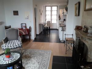 a living room with a clock on a fireplace and a table at Petite Maison Romantique Coeur Historique Plantagenet, au calme in Le Mans