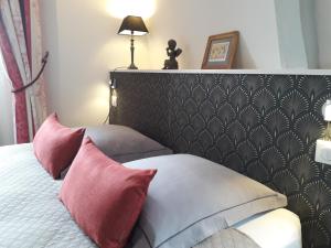 a bedroom with a bed with red and white pillows at Petite Maison Romantique au calme, Cœur Historique, vue Ville et Jardin in Le Mans