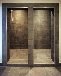 W łazience z wyłożoną kafelkami ścianą znajduje się prysznic. w obiekcie Horsky Hotel Sliezsky Dom w mieście Tatrzańska Polanka