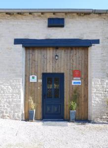 a blue door on a brick building with two plants at Gîte de la Côte in Viéville