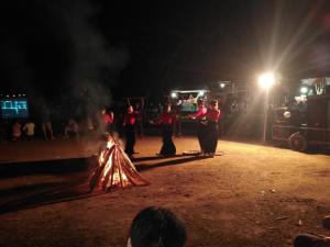 a group of people standing around a fire at night at Green Homestay Mai Chau in Mai Châu